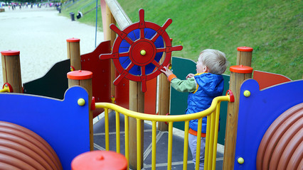 Dziecko na statku na placu zabaw przy kole sterowym bawi się