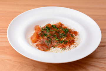 Rice with beef stew with green beans and vegetables served in white plate over light rustic wooden table.