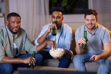 friendship, leisure and people concept - happy male friends with beer and popcorn watching tv at home at night