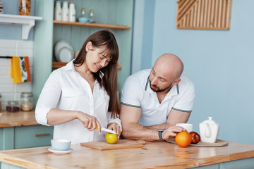 Obraz na płótnie Canvas A young beautiful couple prepares Breakfast together in the kitchen on a weekend morning. Romantic relationships, love, family