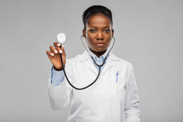 medicine, profession and healthcare concept - african american female doctor in white coat with...