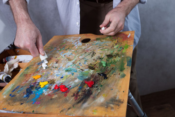 The artist squeezes paint from a tube onto a palette. Close-up