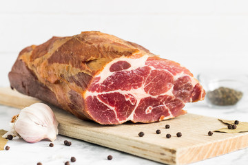 Smoked ham on wooden cutting board with garlic and spices