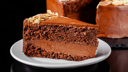 Modern pastry. Chocolate cake with nuts, almonds and peanut butter. Cake on a black background. background image, copy space text