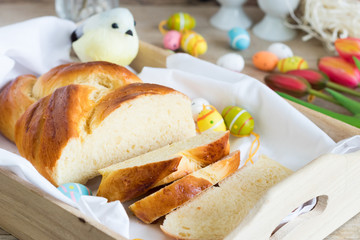 Sliced sweet braided bread on tray with easter decoration in the background.