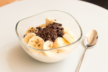 Healthy snack bowl with natural yogurt, banana and dark chocolate