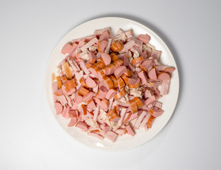 Meat and sausage slices. Preparation for soup Solyanka. A pile of chopped slices on a white round plate. View from above