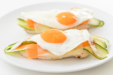 Baked chicken breast with zucchini carrot and fried egg on top.