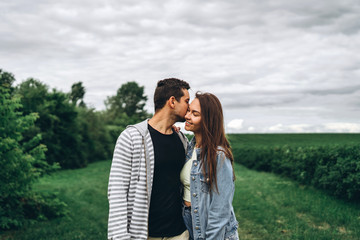 Young loving couple, woman and man, gently hugging with eyes closed on the background of green field. Love Story