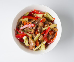 Korean meat salad in a white bowl. View from above. Juicy salad of beef, cucumbers, peppers
