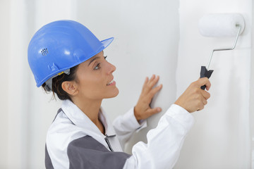 woman painting the wall with paint roller