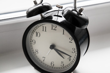 An alarm clock stands on a window in the morning light.