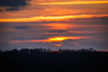 Fototapeta premium evening sun behind the clouds over the forest