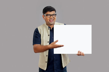 Man showing and pointing at a square placard in his hand. 