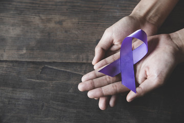 Woman Hand Holding Purple Ribbon, Domestic Violence Awareness Month (October) concept with deep purple awareness ribbon. - obrazy, fototapety, plakaty