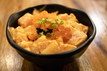 Spicy salmon with ikura don in black bowl. Japanese food