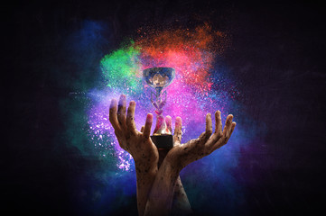 Hand holding up a gold trophy cup against dark background