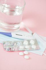 Medical masks, medications, pills, pills, thermometer and syringe for the coronavirus epidemic. A set of medicines for the treatment of coronavirus lies on a pastel background. Selective focus.