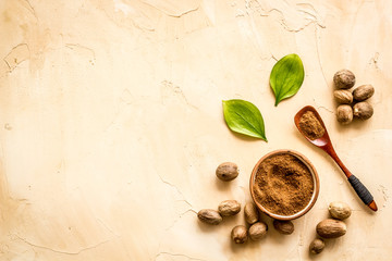 Nutmeg - ground indian condiment in spoon - on beige background top-down copy space