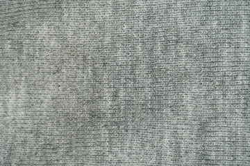Grey knitted fabric textured background close up view.