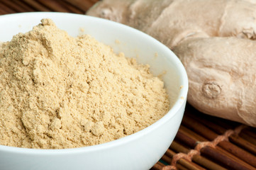 Powdered ginger in a bowl and whole ginger