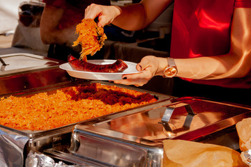 Woman in red serve hot dog with sour cabbage at the food market stall