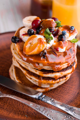 Delicious and lush pancakes with fresh fruits and berries, poured with salted caramel.