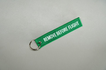 Dark green remove before flight airplane safety label isolated on white close up.