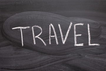 The inscription in white chalk on a black blackboard with the word travel