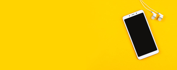 White smartphone and headphones on an yellow background. The template for a music app or web site