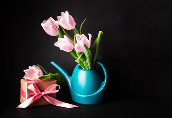 A beautiful bouquet of pink tulips in a water can on a dark background.