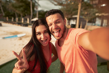 Handsome smiling couple having fun together taking a selfie photo at the beach bar