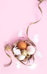 Easter composition with eggs and paper rabbit on pink pastel background. Flatlay 