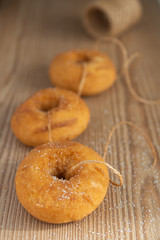 Top view of three donuts with roll of rope, on wooden board, with unfocused background, in vertical