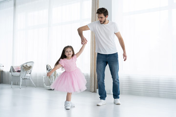 I love you, dad! Handsome young man is dancing at home with his little girl. Happy Father's Day!