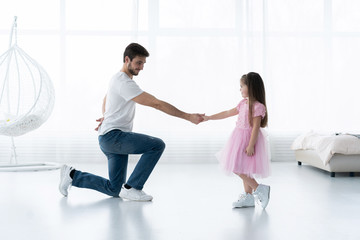 Fototapeta premium I love you, dad! Handsome young man is dancing at home with his little girl. Happy Father's Day!