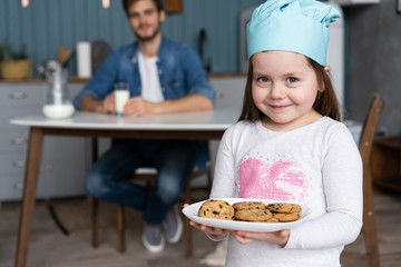 cute little girl holding a baking sheet of cookies.