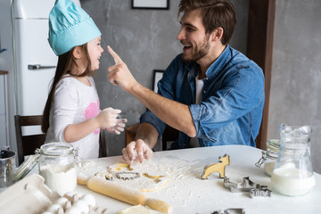 Happy father and daughter having fun while cooking together.