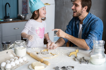 Happy father and daughter having fun while cooking together.