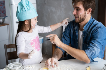 Happy father and daughter having fun while cooking together.