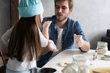 Happy father and daughter having fun while cooking together.