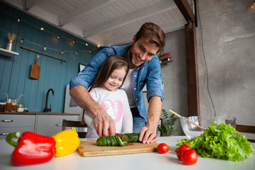 Handsome man and his little cute daughter are cooking on kitchen. Making salad. Healthy lifestyle concept.
