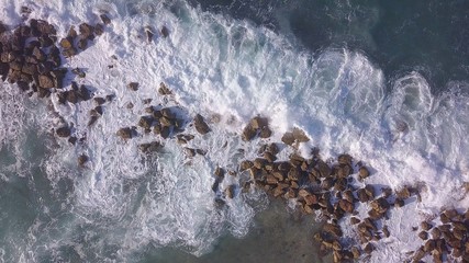 Ocean waves are breaking on a Breakwater at winter sea. Aerial top down view.