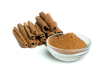 Powdered cinnamon in bowl and cinnamon sticks