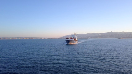 Aerial shot of container ship in ocean. Loaded vessel moves at calm water.