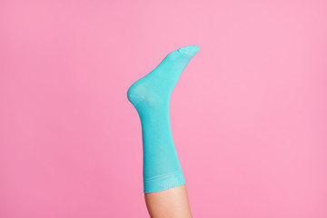 Cropped close-up view of one nice single leg wearing blue soft cotton bright sock isolated over pink pastel color background