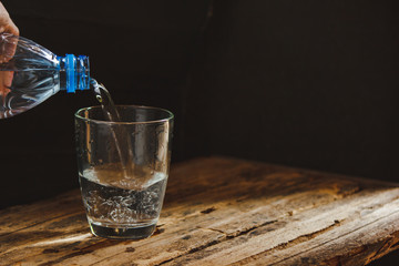 A man's hand is pouring water in a glass