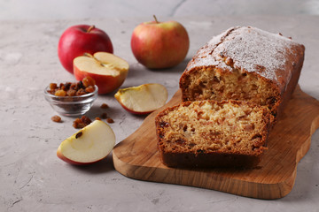 Homemade muffin with apples and raisins on a wooden board on a gray background