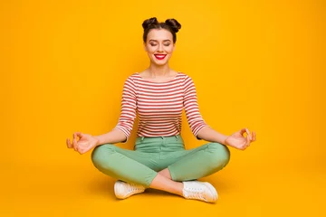 Keuken spatwand met foto Full body photo of pretty lady hold fingers together lotus position sit floor legs crossed eyes closed wear striped red white shirt green pants footwear isolated yellow color background © deagreez