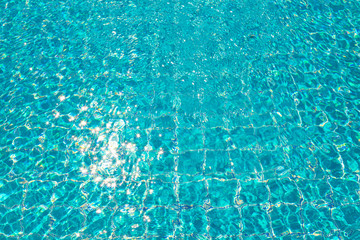 A blue water ripple in the pool with star shape of sunlight reflect on surface